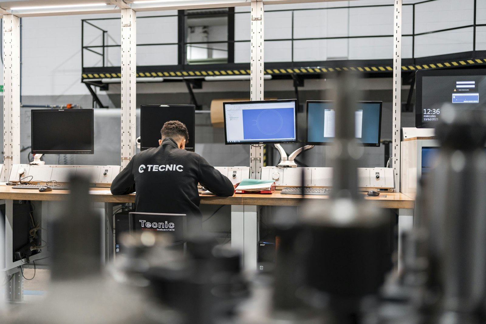 Engineer analyzing live production data across multiple monitors on an industrial floor